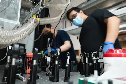 Oumeng and Yuanxin align a laser in lab